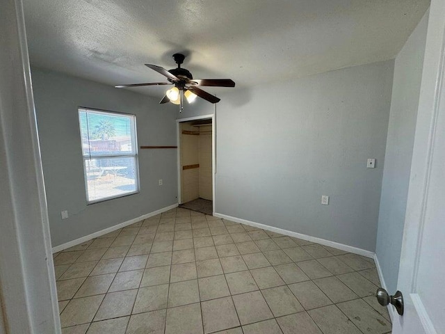 spare room with a textured ceiling, ceiling fan, and light tile patterned flooring