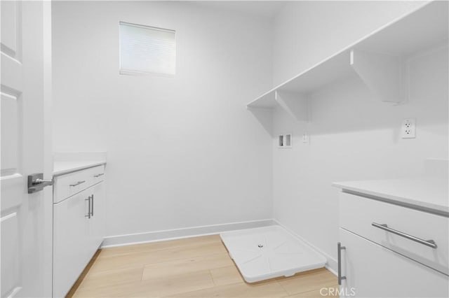 washroom featuring cabinets, hookup for a washing machine, and light wood-type flooring