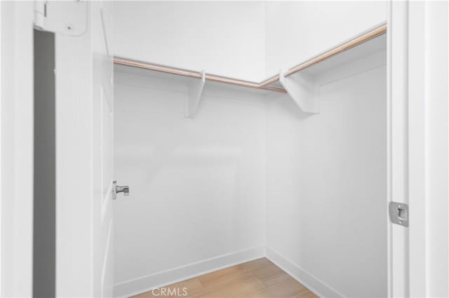 walk in closet with light hardwood / wood-style flooring