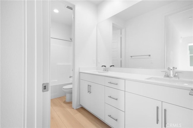 full bathroom featuring toilet, shower / washtub combination, hardwood / wood-style floors, and vanity