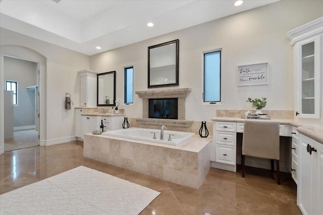 bathroom with a wealth of natural light, tile patterned flooring, tiled tub, and vanity