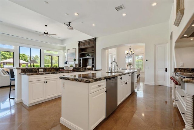 kitchen featuring white cabinetry, dark stone countertops, dishwasher, and a kitchen island with sink