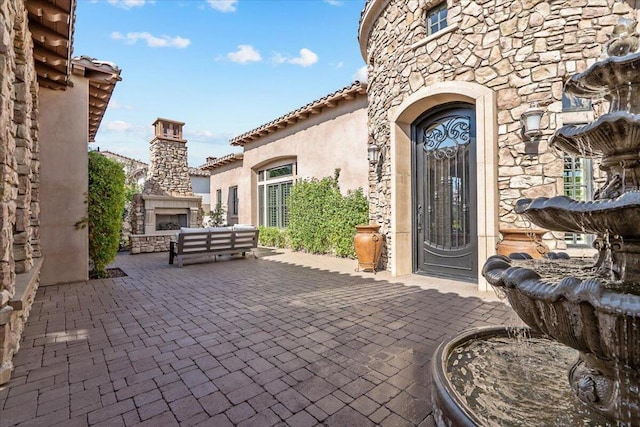 entrance to property with a patio area and an outdoor living space with a fireplace