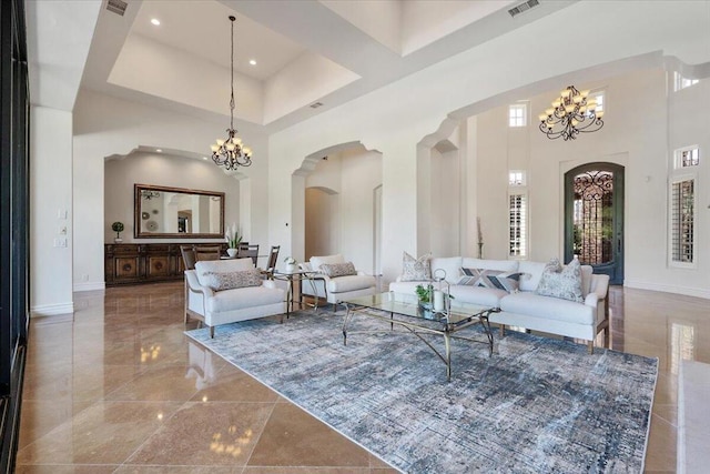 living room featuring a chandelier, a towering ceiling, and a healthy amount of sunlight