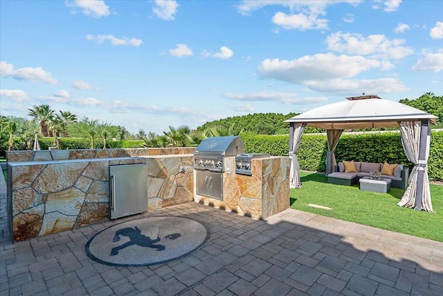 view of patio / terrace featuring a grill, a gazebo, outdoor lounge area, and exterior kitchen