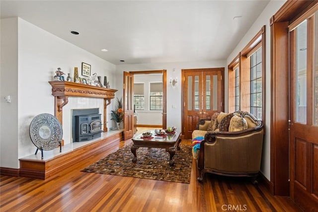 living room with wood-type flooring, a wealth of natural light, and a wood stove