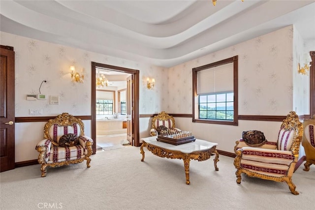 sitting room featuring carpet floors, an inviting chandelier, and a raised ceiling