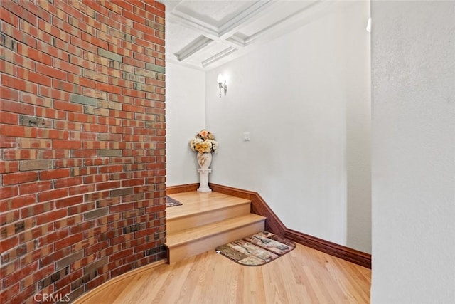 hall with beamed ceiling, wood-type flooring, brick wall, and coffered ceiling