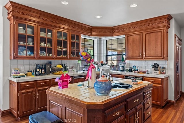 kitchen featuring a center island, sink, dark hardwood / wood-style floors, backsplash, and tile countertops