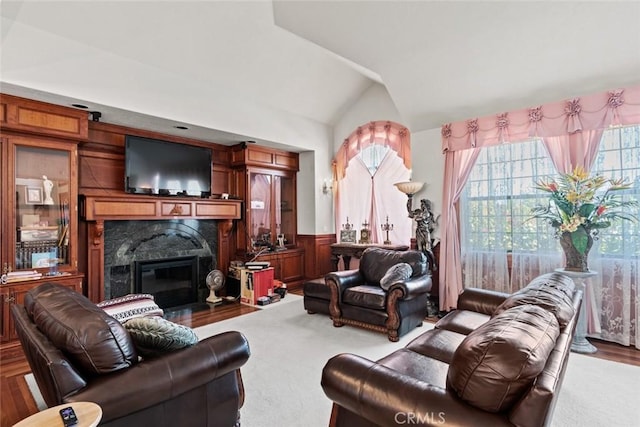 living room with wood walls, a fireplace, carpet, and vaulted ceiling