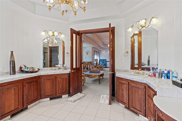 bathroom featuring vanity, a raised ceiling, and a notable chandelier