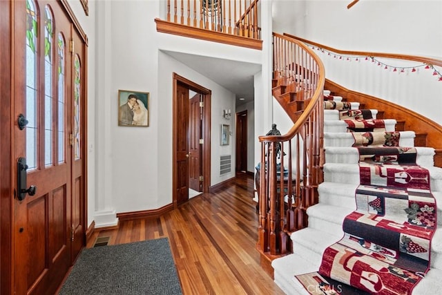 foyer with hardwood / wood-style floors and a towering ceiling