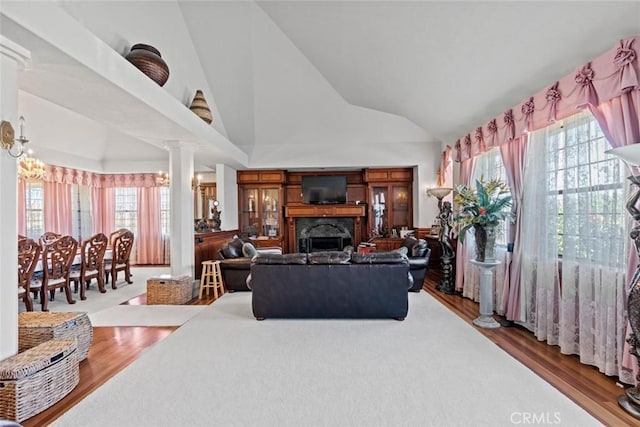 living room featuring ornate columns, plenty of natural light, high vaulted ceiling, and hardwood / wood-style flooring