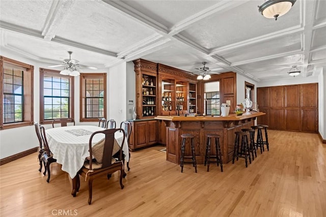 dining space with coffered ceiling, ceiling fan, light hardwood / wood-style floors, and bar area