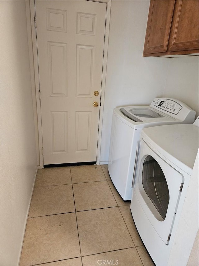 laundry room with cabinets, light tile patterned flooring, and washing machine and clothes dryer