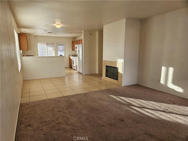 unfurnished living room featuring light colored carpet and a tiled fireplace