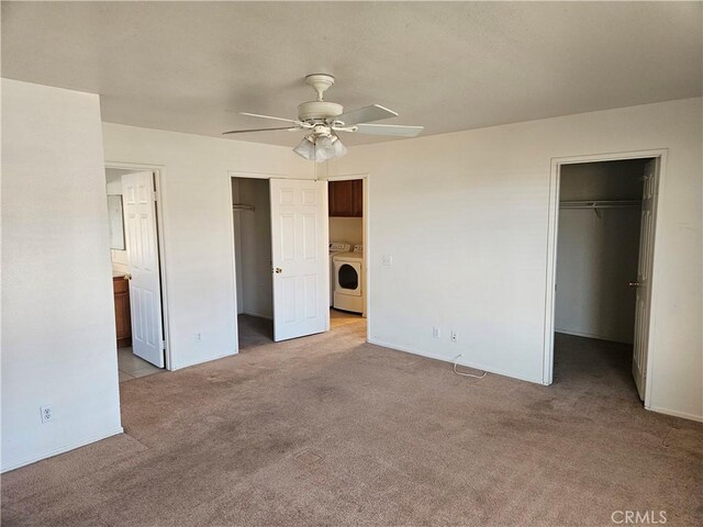 unfurnished bedroom featuring light carpet, ceiling fan, ensuite bath, a walk in closet, and washer / clothes dryer