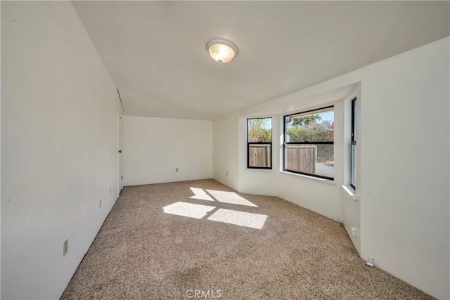 empty room featuring light carpet and vaulted ceiling