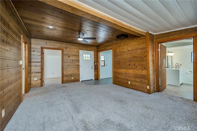 carpeted spare room featuring wood ceiling, ceiling fan, and wood walls