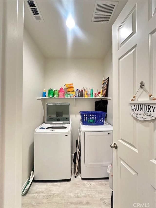 laundry room with light hardwood / wood-style flooring and washer and dryer