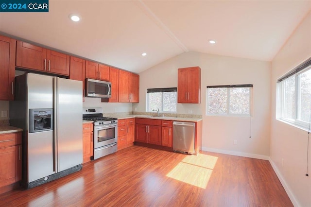 kitchen with light hardwood / wood-style floors, sink, stainless steel appliances, and vaulted ceiling