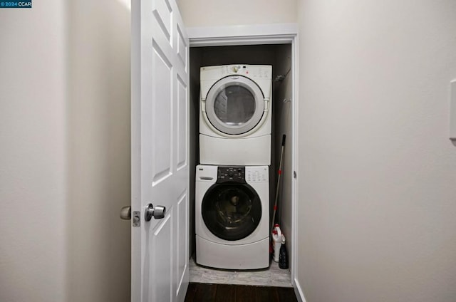 laundry area featuring dark hardwood / wood-style flooring and stacked washing maching and dryer