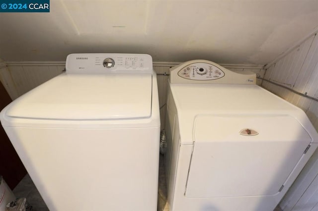 laundry room with separate washer and dryer and wooden walls