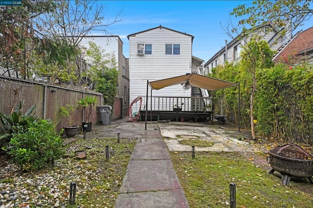 rear view of property with a deck and a fire pit