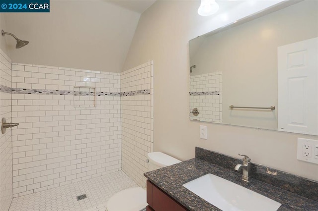 bathroom featuring toilet, vanity, lofted ceiling, and tiled shower