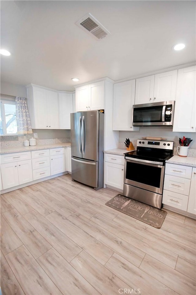 kitchen featuring white cabinetry, stainless steel appliances, and light hardwood / wood-style flooring