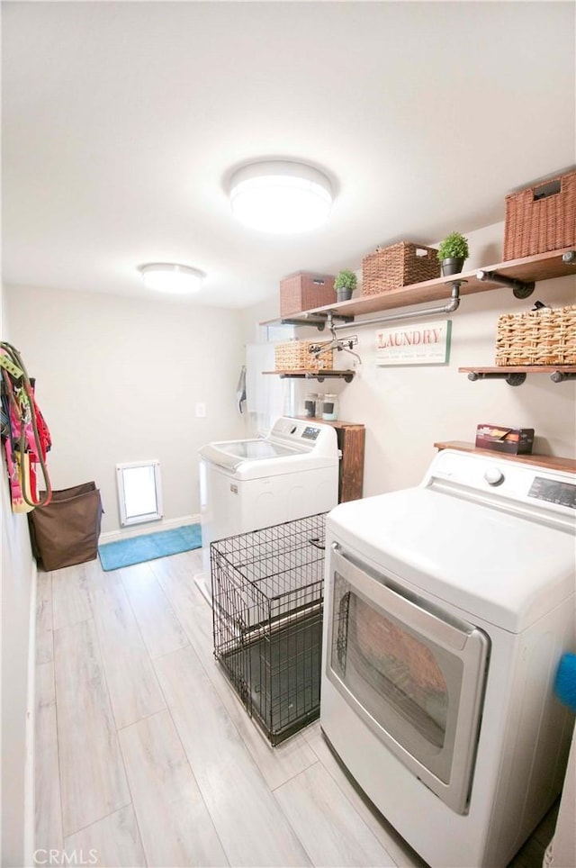 clothes washing area with washing machine and dryer and light hardwood / wood-style floors