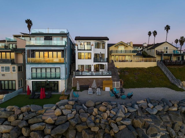 back house at dusk featuring a patio area and a yard