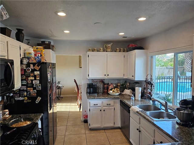 kitchen with black appliances, sink, light tile patterned flooring, white cabinetry, and dark stone counters