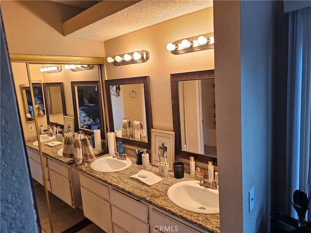 bathroom with a textured ceiling, tile patterned flooring, and vanity