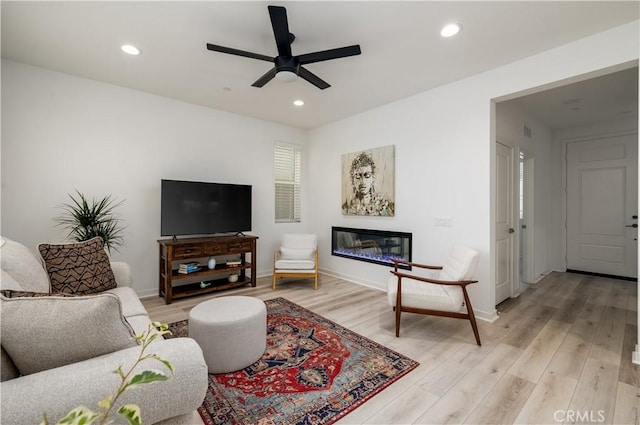 living room with ceiling fan and light hardwood / wood-style flooring