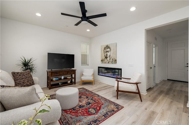 32879 Brunello Way, Temecula, CA 92591 - living room featuring a ceiling fan, light wood finished floors, a glass covered fireplace, and recessed lighting