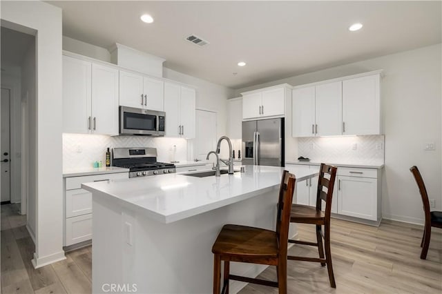 32879 Brunello Way, Temecula, CA 92591 - kitchen featuring stainless steel appliances, a breakfast bar area, tasteful backsplash, light wood finished floors, and a center island with sink