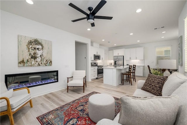 living room with ceiling fan and light hardwood / wood-style floors