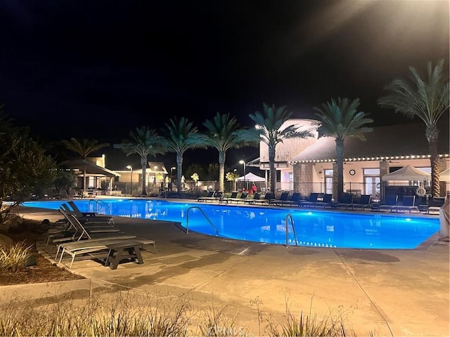 pool at night featuring a patio