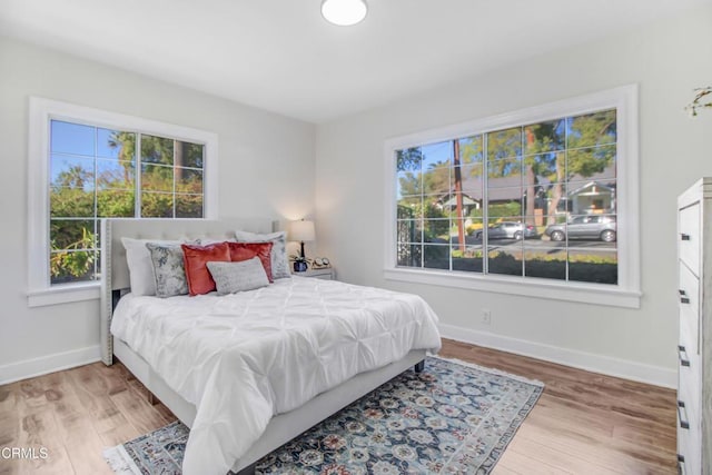 bedroom with light hardwood / wood-style floors and multiple windows