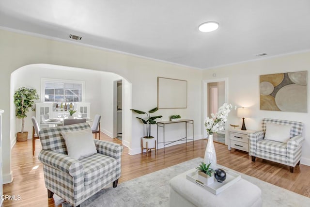 living room with ornamental molding and light hardwood / wood-style flooring