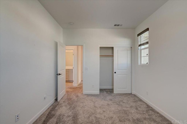 unfurnished bedroom with light carpet and a closet