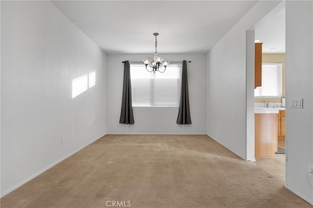 empty room featuring plenty of natural light, light carpet, and a notable chandelier