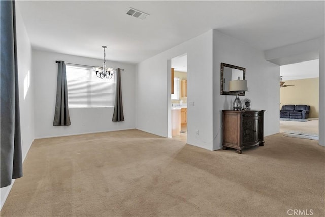 carpeted spare room featuring a notable chandelier