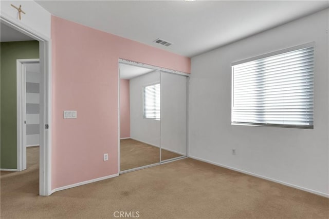 unfurnished bedroom with light colored carpet and a closet