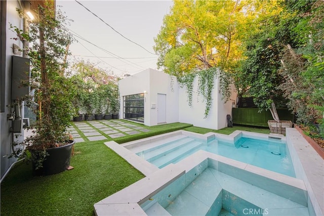 view of pool with an in ground hot tub and a lawn