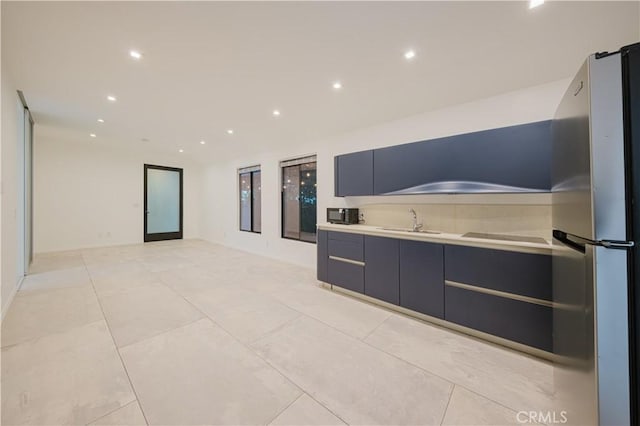 kitchen featuring stainless steel fridge, light tile patterned floors, and sink