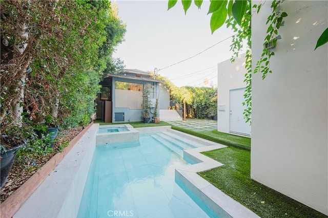 view of swimming pool featuring a lawn and an in ground hot tub