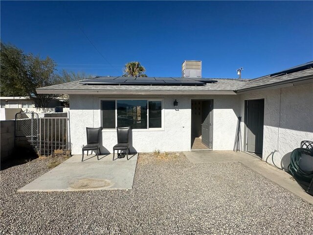 rear view of house with solar panels and a patio