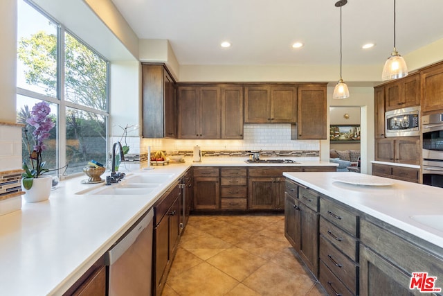 kitchen featuring sink, stainless steel appliances, decorative light fixtures, decorative backsplash, and light tile patterned flooring